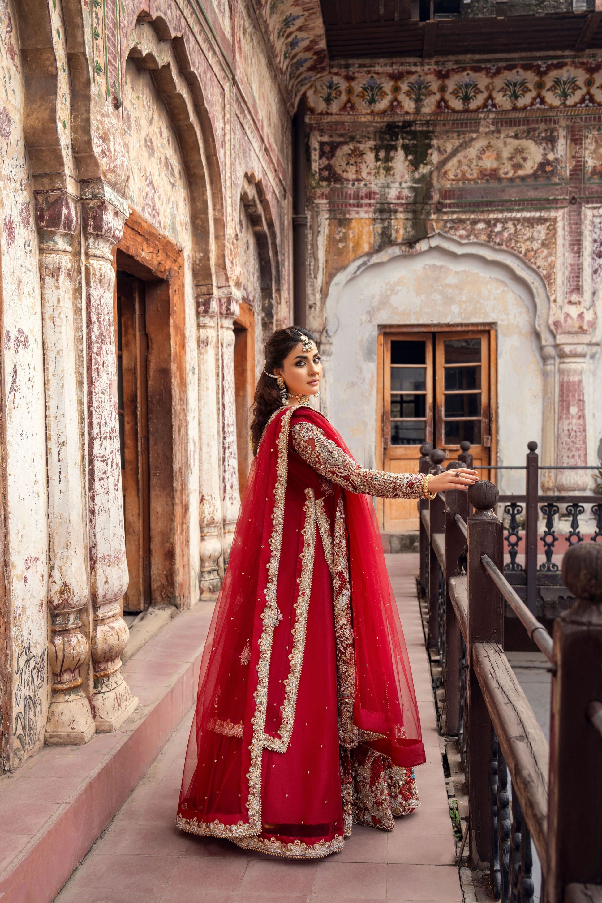 Woman in a red traditional outfit standing in an ornate architectural setting