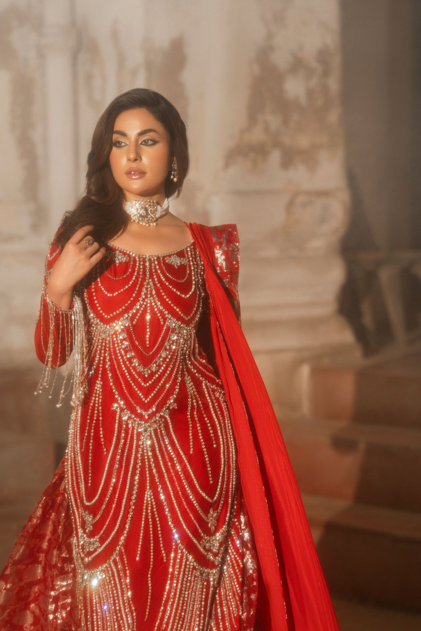 Woman in a red and gold traditional outfit with intricate designs.