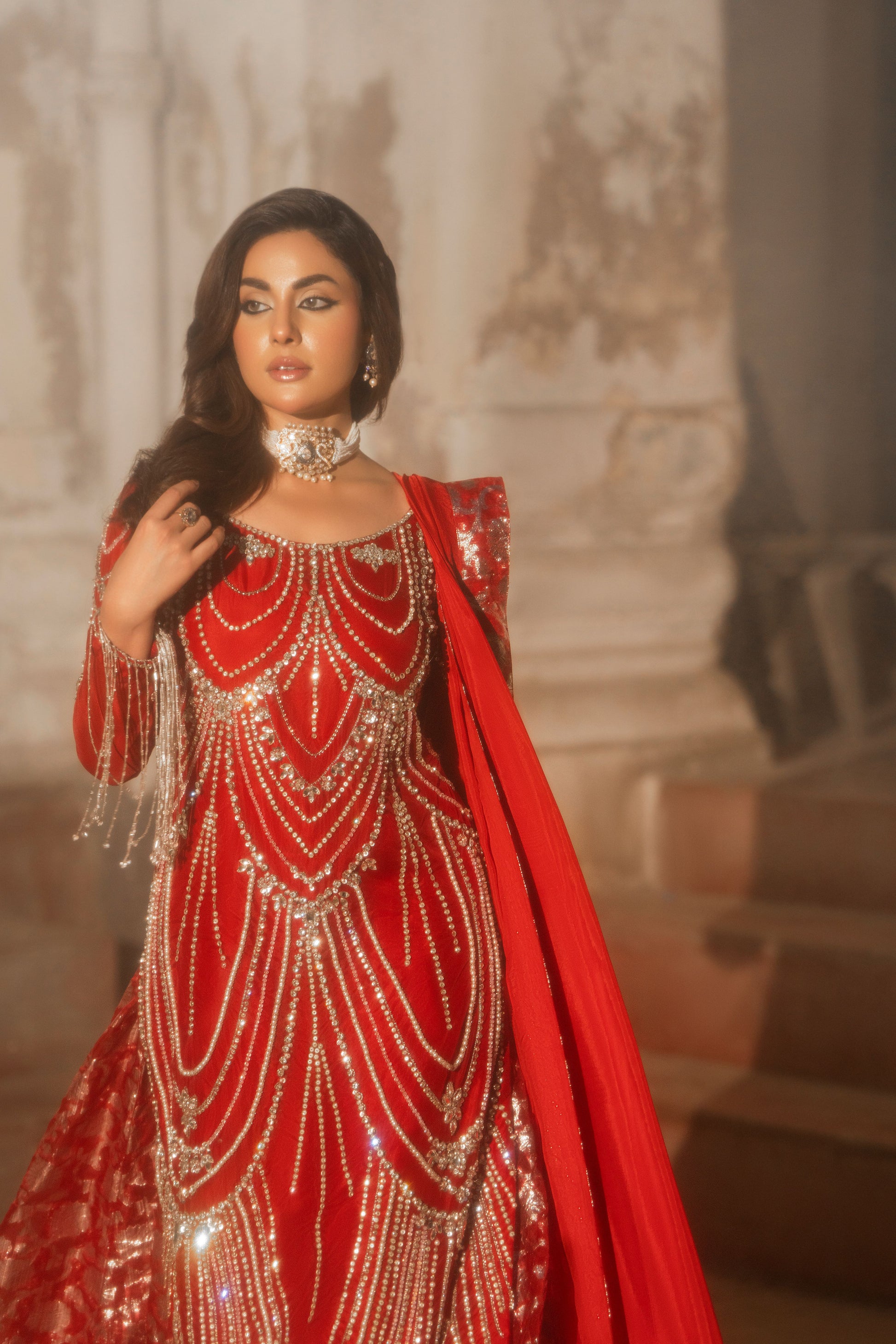 Woman in a red and gold traditional outfit with intricate designs.