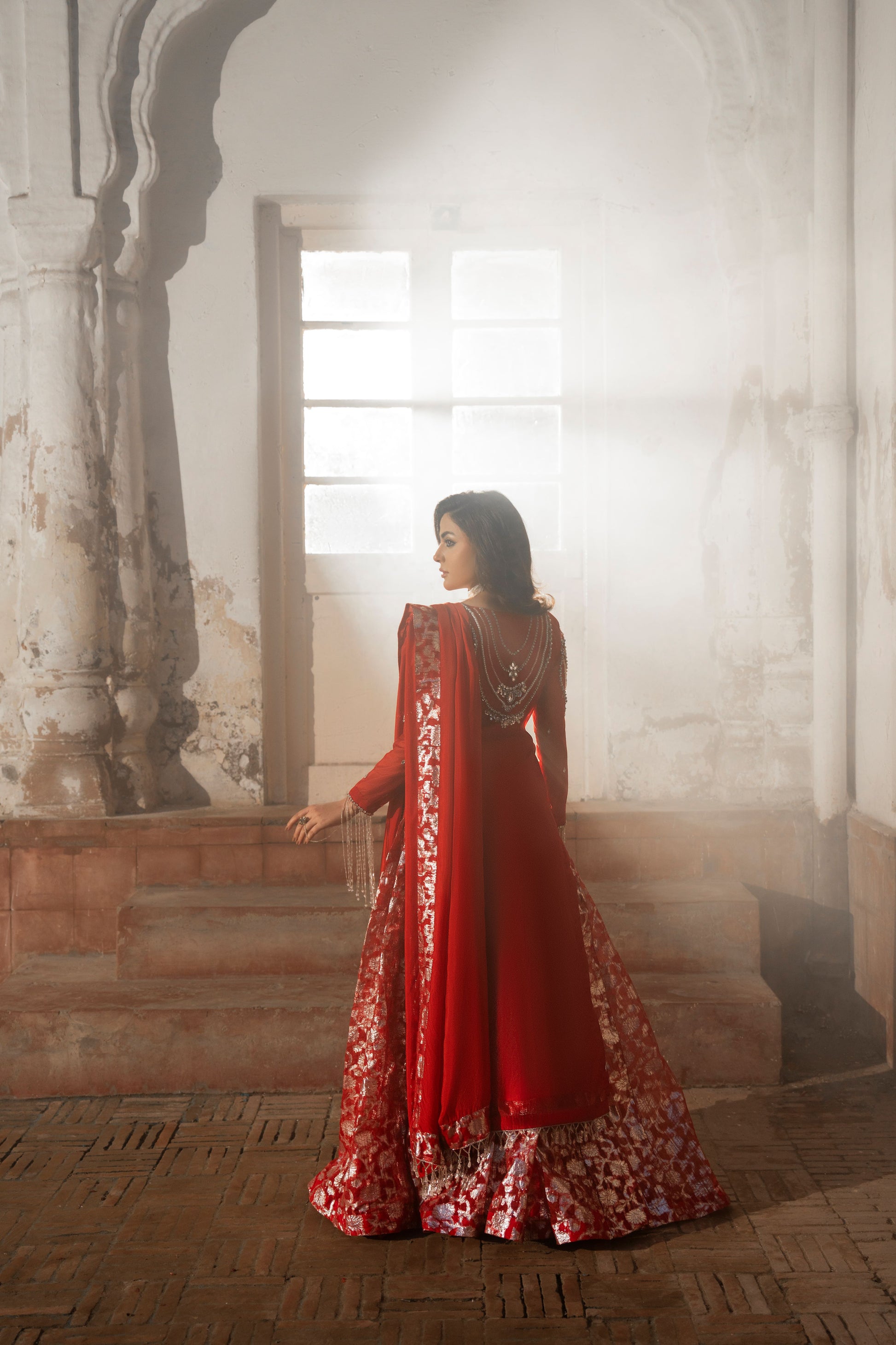 Woman in a red traditional outfit standing in an architectural setting