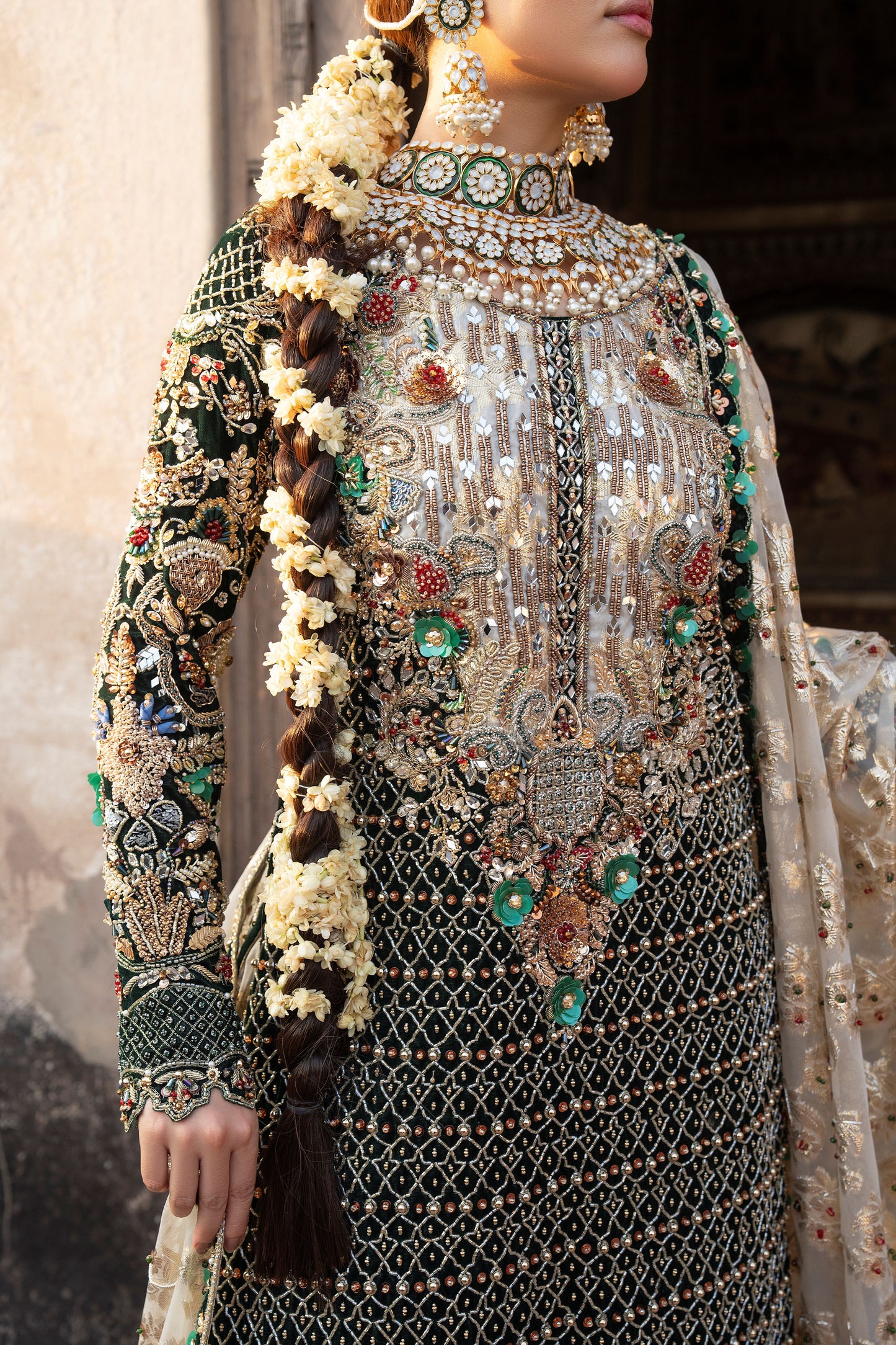 Person wearing an intricately designed traditional outfit with jewelry and floral hair accessories.