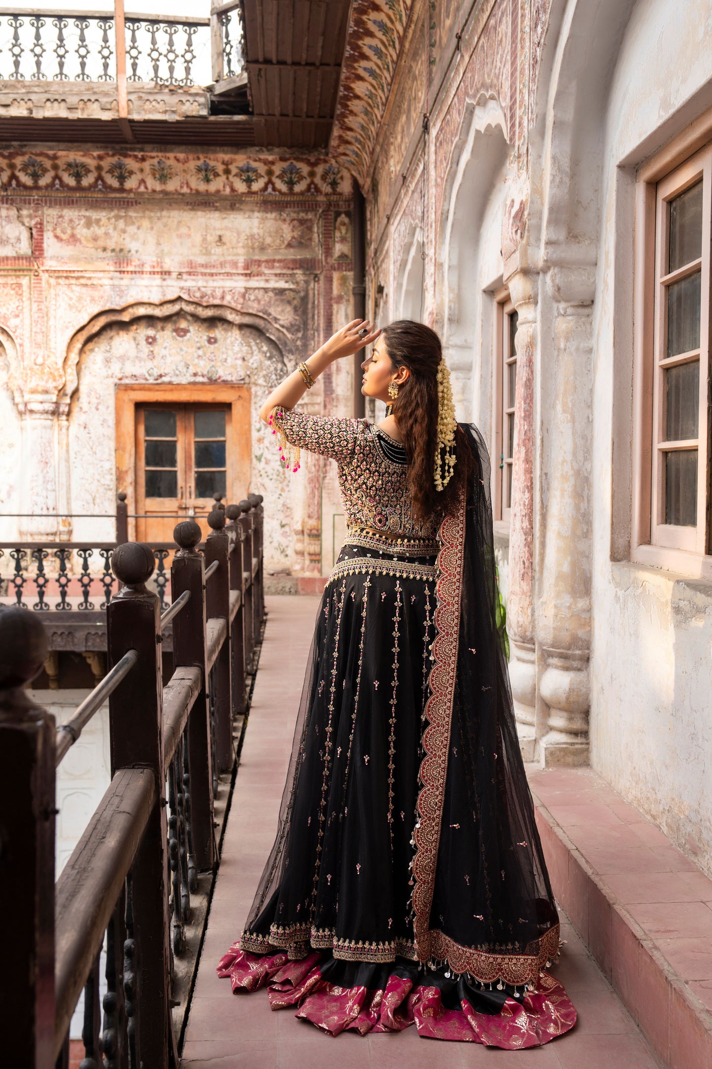 Woman in traditional black and gold outfit standing in an architectural setting