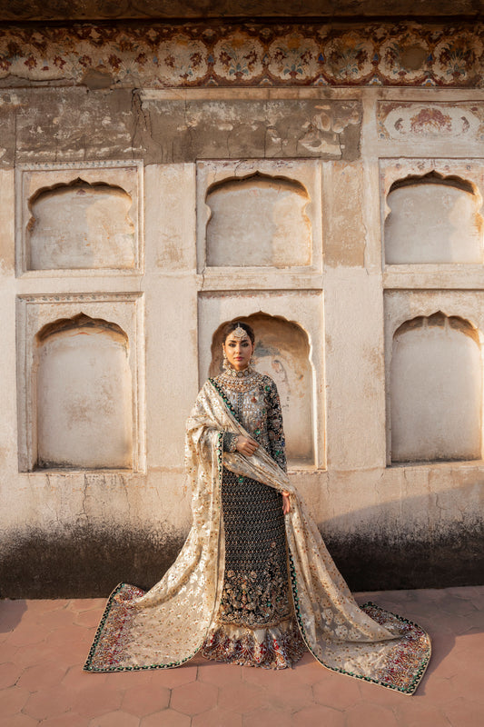 Woman in traditional attire standing in front of an architectural wall with arched niches.