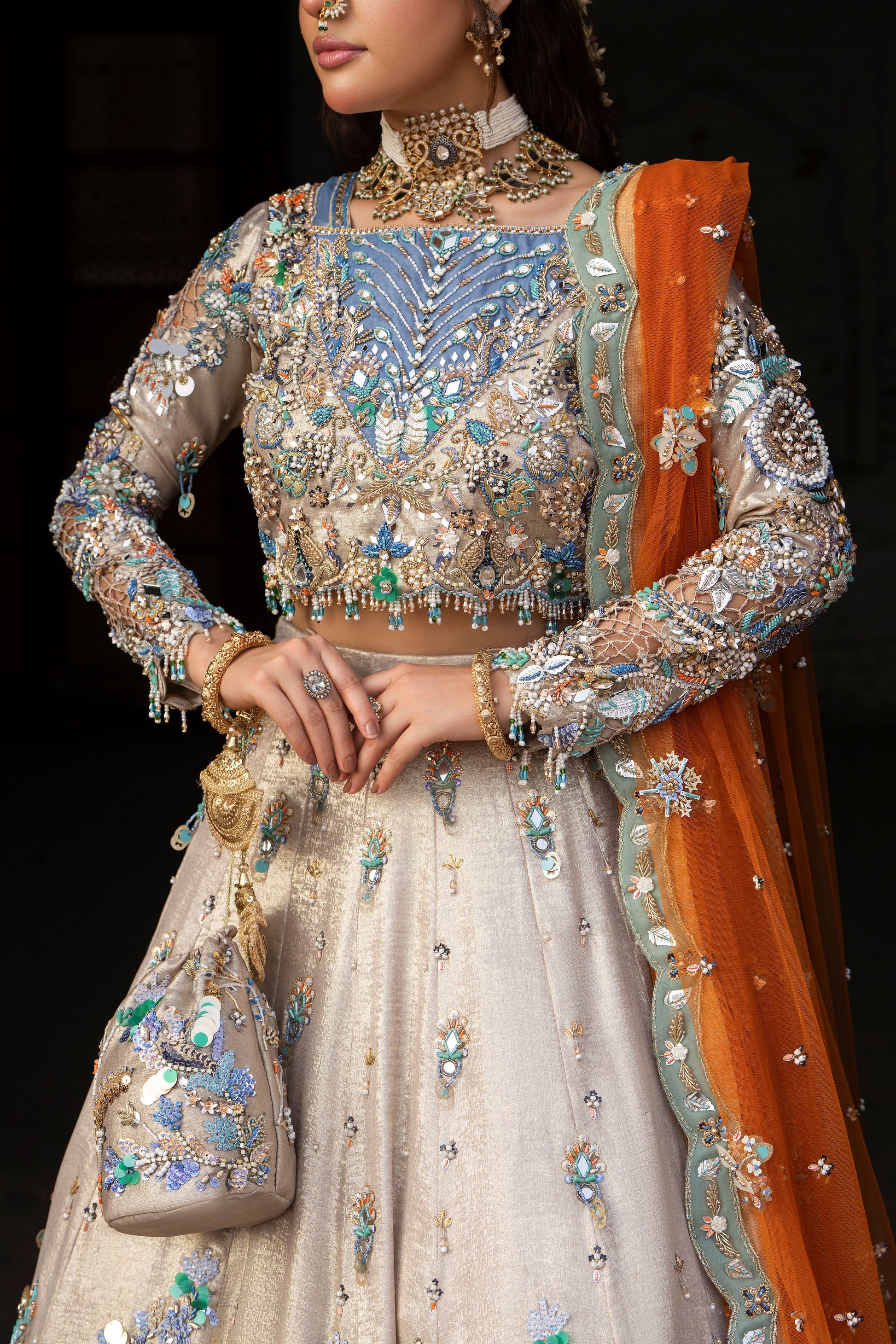 Woman wearing an intricately designed traditional outfit with embroidery and jewelry.